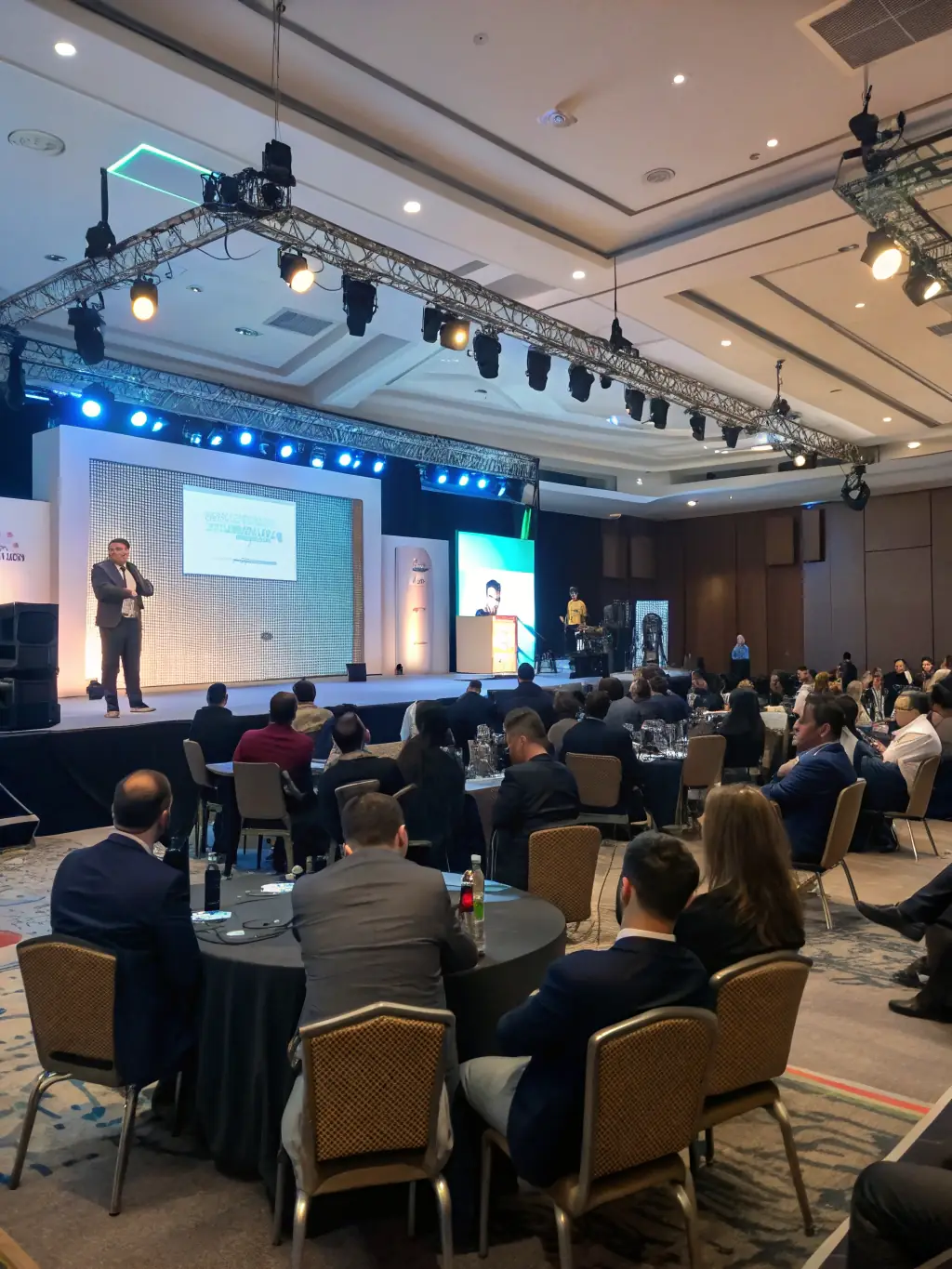 A panoramic view of a ColiseumSpot conference venue, showcasing the overall atmosphere, including exhibitor booths, presentation stages, and attendee interactions.